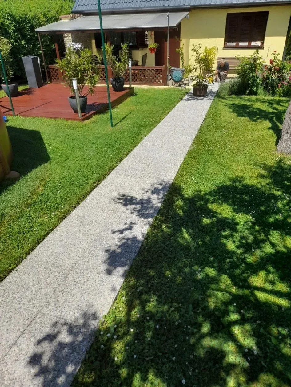 Gepflegter Rasen beidseits eines Plattenwegs zur Terrasse